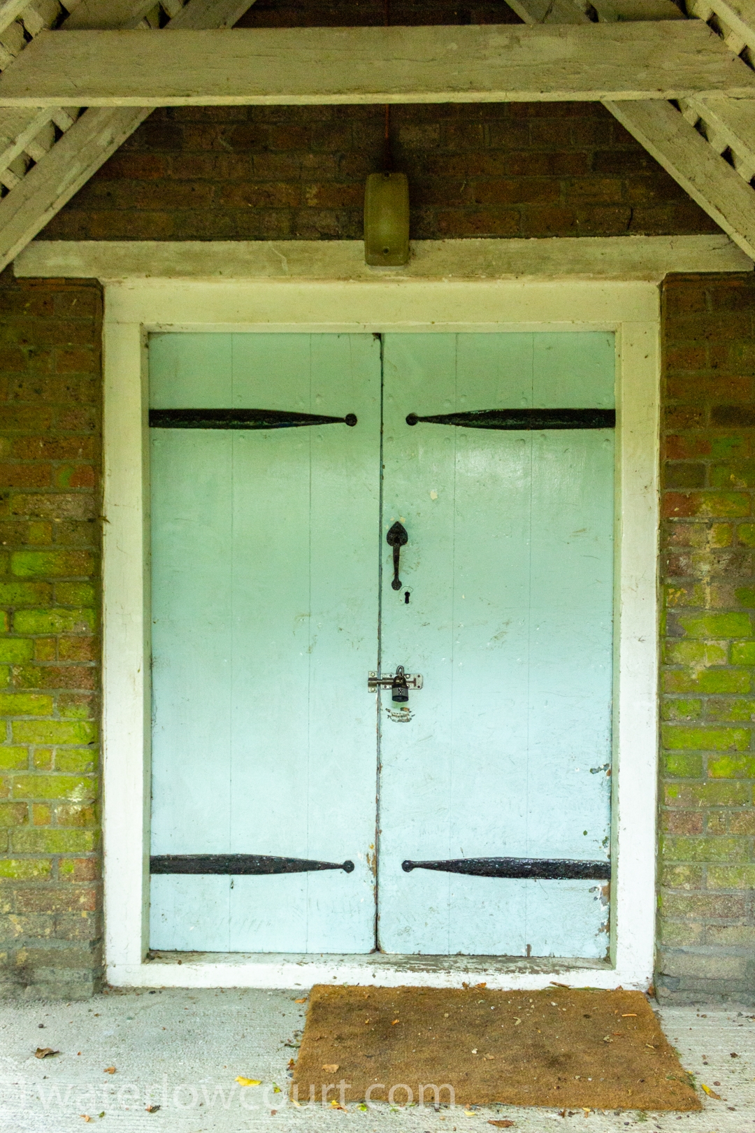 The light-blue oak plank doors on the bicycle shed at Waterlow Court. Waterlow Court is an Arts & Crafts Grade II* listed building, designed by M. H. Baillie Scott, 1909, located in Hampstead Garden Suburb, London NW11 7DT. Flat 1, a one-bedroom, ground-floor flat, is for sale. Listed on Rightmove and Zoopla.